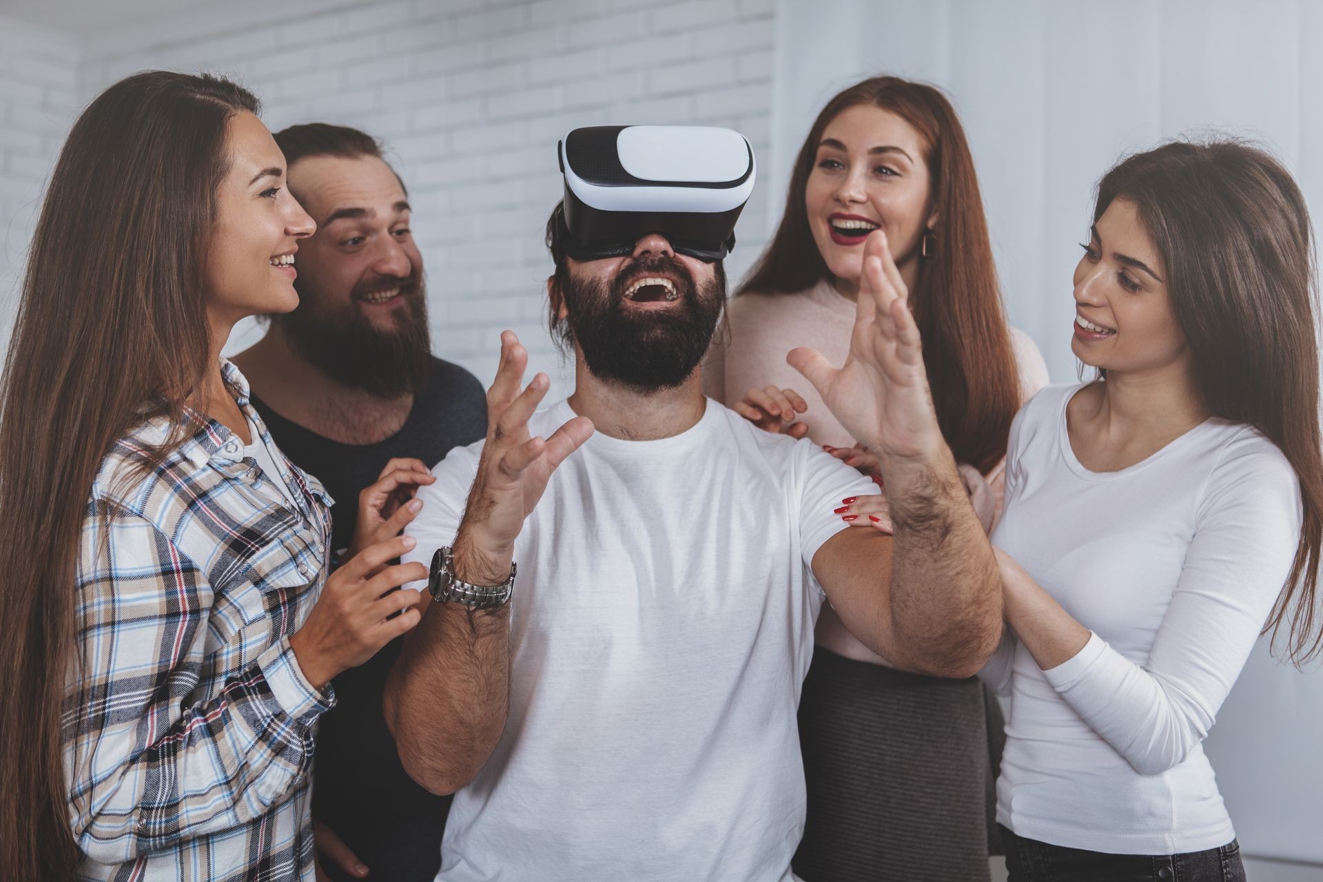 Group of friends , wearing virtual reality glasses. Team of creative designers using 3d vr goggles at work. Bearded man looking excited, trying virtual reality headset